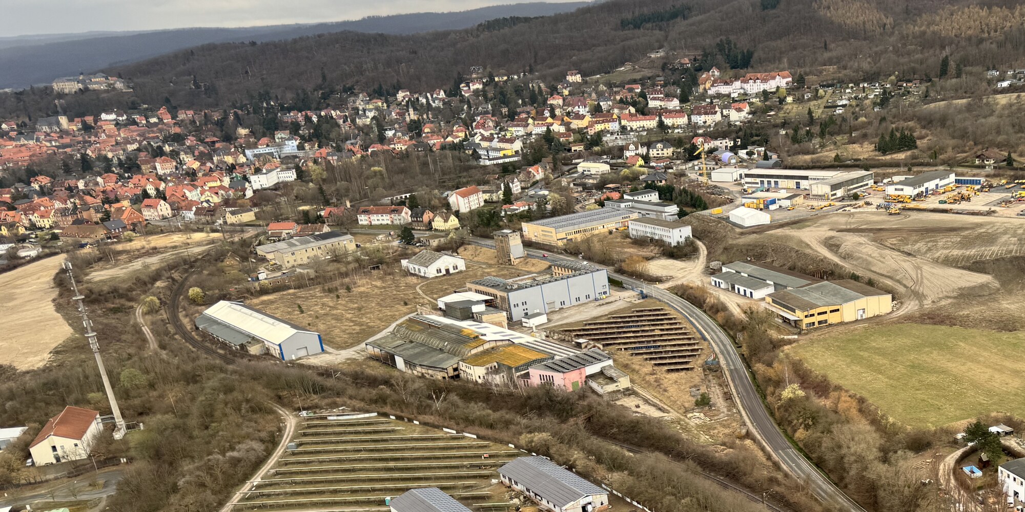 Oblique aerial of Blankenburg from the north: the old town on the hillside, an industrial belt along the railway, halls and open ground in the foreground