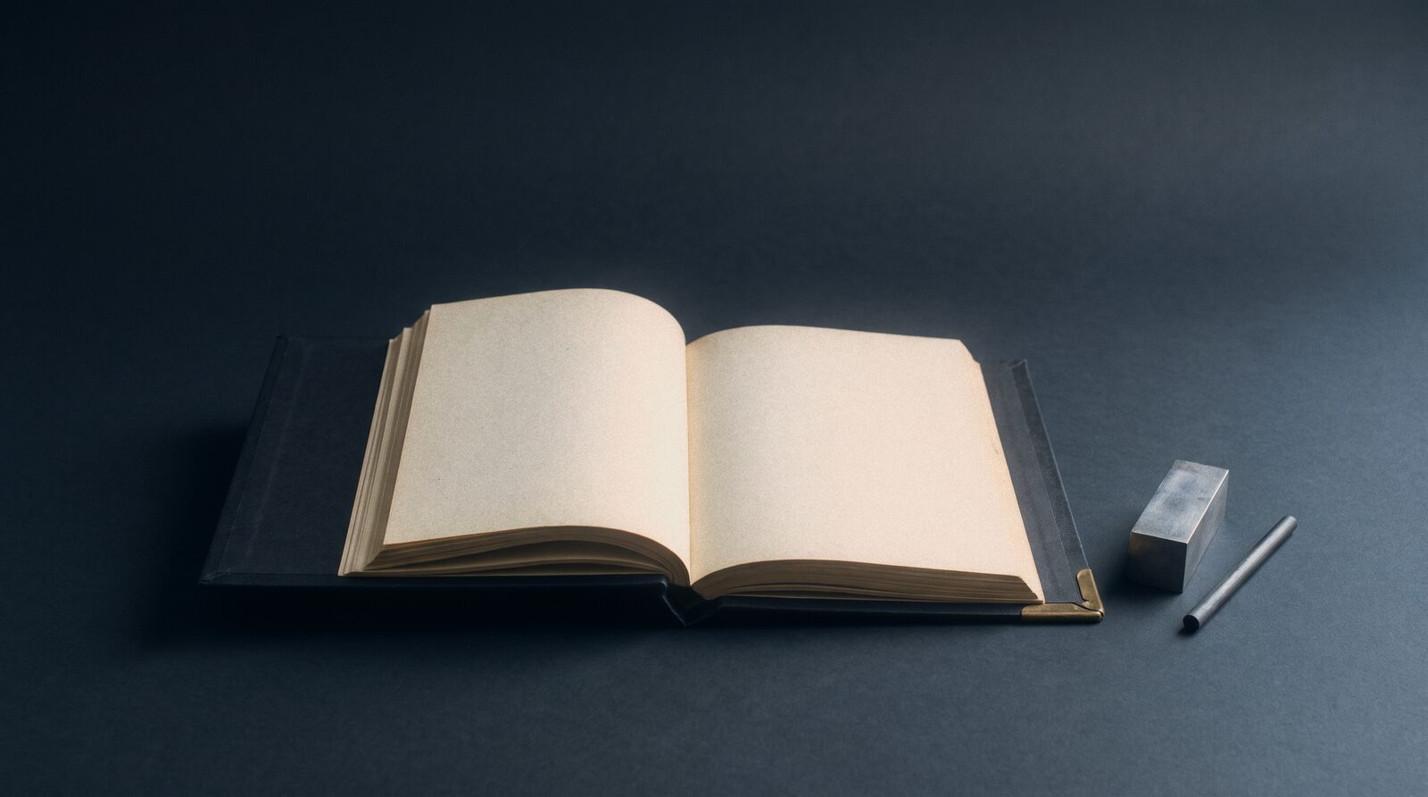 A bound ledger lying open, dark cover, cream pages
