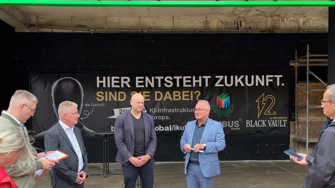 The press briefing in front of the building, officials and the developer before the Black Vault banner